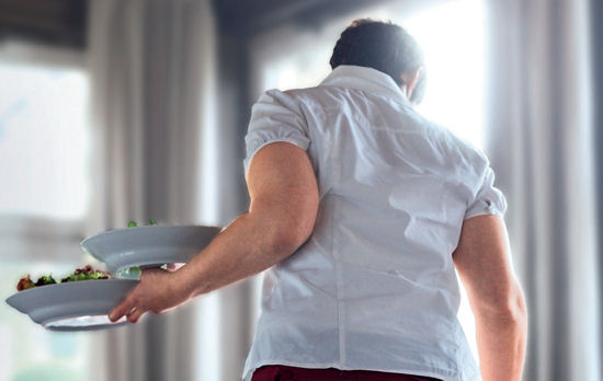 Bedienung mit zwei Tellern auf einem Arm