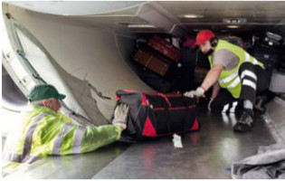Ein Arbeiter kniet im Gepäckraum eines Flugzeugs